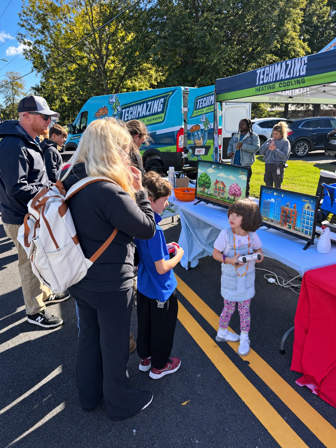 A young festival visitor holds a controller beside the game stations.